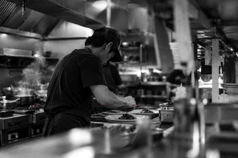 Line cook plating food in a busy independent restaurant kitchen